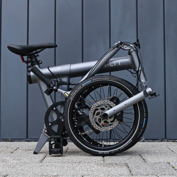 FLIT M2 folding ebike, folded in front of a grey wall in Cambridge